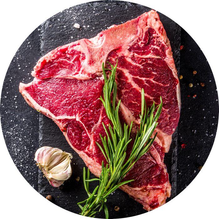 belle pièce de boeuf avec une branche de romarin et de l'ail posée sur une ardoise grise